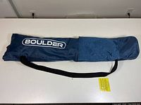 Blue carrying case labeled Boulder containing the packed net with black strap for transport.