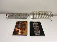 Two vintage metal 45 record racks and two Neil Gaiman Sandman hardcover books arranged on a white surface.