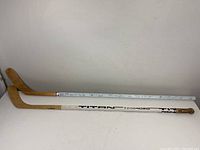 Two hockey sticks side by side, one white and one wood, each with signatures on the shaft.