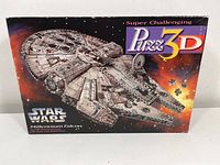 Front of the box showing Star Wars Millennium Falcon 3D Puzzle with 857 pieces and branding.