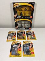 Two unopened 6-pack boxes of Kenner Action Masters die cast Star Wars figures and five unopened single-pack figures laid out in front, including R2-D2 and others.