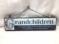 Full front view of the wooden wall decor sign with quote about grandchildren, showing the entire text and hanging wire.