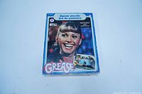 Front of puzzle box showing image of actress from Grease and logo with puzzle piece count