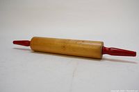 Full length photo showing the wooden rolling pin with red handles and the overall shape and condition.
