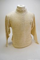 Full front view of cream knit cardigan on mannequin showing long sleeves and stand collar with button row.