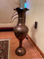 Full view of the India brass vase showing its tall, slender form with a flared, wavy rim and decorative engravings.