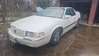 White Cadillac Eldorado ETC parked at driveway, front passenger 3/4 view