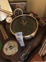 Wide view showing the assortment of clocks including a large round clock with metal rim, small travel clocks, and clock radio on dresser.
