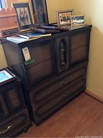 Front and side view of a 4 drawer wood veneer dresser with decorative metal handles and slightly curved drawer fronts.