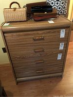 Front view of the dresser showing four drawers with wooden pulls and arborite wood grain finish.