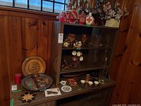 Shelving unit with assorted carved wood items, metal and silver plate trays, plastic and china dishes, and small decorative items.