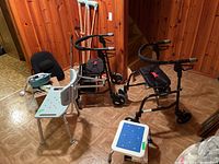 Wide view of lot showing two Nexus rollators, shower chair, stool, crutches and miscellaneous items