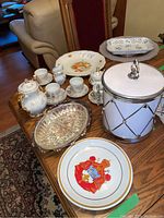 Wide shot showing the entire collection on a wooden table, including cups, coffee pot, plates, ice bucket, and pickle tray.