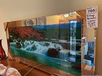 Front view of vintage 3D waterfall wall hanging with red flowers and water flowing effect, encased in clear material and framed with wood.