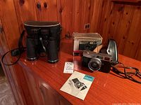 Full view of Canon Canonet camera with original box, booklet, and Focal binoculars with case.