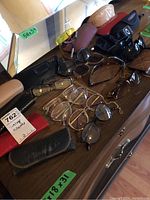 Wide assortment of ladies eyeglasses, sunglasses, many cases and accessories arranged on a table