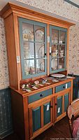 View of the two piece country cabinet made of pine and painted pine with glass paneled upper doors and painted lower doors and drawers.