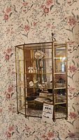 Crystal and brass-framed display cabinet with glass panels and mirrored back, containing crystal miniatures and clock