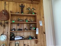 Shelf mounted on a wood-paneled wall holding a collection of duck figurines and a totem pole figure arranged across three shelves.
