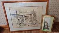 Original framed sketch showing a brick house, man on roof, wagon and a dog sketch next to it in a gold frame.