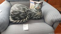 Full view of the paper mache cat figurine on a chair.