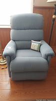 Front view of blue upholstered La-Z-Boy recliner with throw pillow on seat.