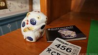 Porcelain harvest mouse figurine next to Royal Crown Derby booklet and auction tag