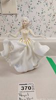Front view of Royal Doulton Sweet Seventeen figurine showing full figure, white dress with yellow and gold accents, and delicate facial features.