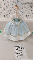 Front view of Royal Doulton figurine in pale blue dress holding fan.