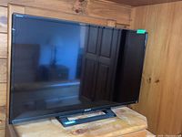 Full front view of Sony 32 inch TV on stand with reflective screen and Sony logo on bottom bezel.