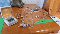 Overview of the jewelry lot showing multiple pieces including brooch, bracelet, ring, necklaces, and earrings on a wooden surface