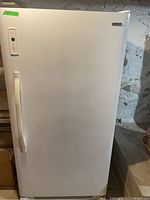 Full view of white upright freezer showing handle and control panel on door.