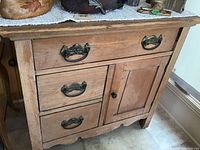 Wooden wash stand showing three drawers with metal handles and a two-door cabinet below.