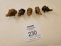 Overhead photo showing all five small elephant stone carvings arranged in a row along with auction number card.