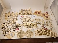 Lot of 44 new, unused wooden Christmas craft ornaments arranged in the tray showing various shapes including reindeer, bells, snowmen, 'BELIEVE' word cutouts, bulb shaped ornaments, and sleighs.