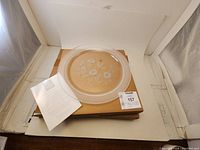 Crystal platter laid flat on a box with an instruction or description sheet beside it. Shows size and design clearly.