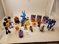 Full view of Disney character figures including Mickey, Minnie, Pluto, Buzz Lightyear, Beast, Snow White, dragon, and others with a white background.