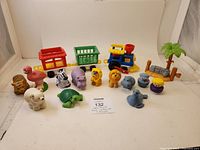 Lot photo showing all items including the full set of 10 animal figures, the train engine and carriages, conductor and clown figures, and palm tree accessory