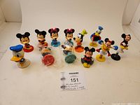 Photo showing 12 Disney character bobblehead and jump-up figurines arranged in two rows against white backdrop