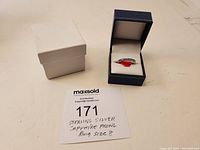 Sterling silver sapphire prong ring displayed in an open blue jewelry box next to a white outer box and a handwritten label.