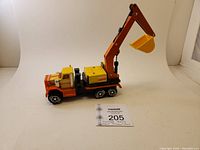 Side view of the vintage ERTL Peterbilt crane digger truck showing the orange cab, yellow crane arm, and black chassis.