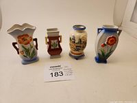 Front view showing all four vases with flower and village designs