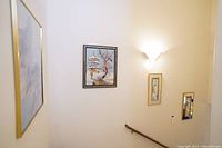 View of the staircase wall showing all three framed Asian-themed paintings at once.