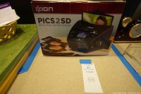 Front view of Ion PICS 2 SD scanner box featuring an image of the scanner with sample photos and film.