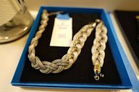 Braided silvertone necklace and bracelet displayed on black fabric in a blue box.
