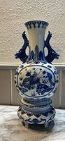 Full front view of the blue and white Japanese porcelain vase on its matching stand, showing dragon and cloud motif.