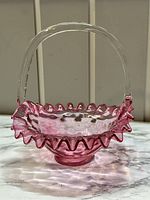 Front view of the LG Wright cranberry glass basket showing the dot optic pattern, ruffled edge, and clear handle.