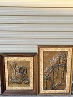Two framed copper embossed relief art pieces: one of a steam locomotive, the other of a person with a horse.