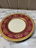 View of first Minton antique dessert or salad plate showing pink border with raised gold floral design and gold rim.
