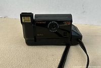 Front angled view of Polaroid Captiva SLR SE camera showing lens, flash, and hand strap attached